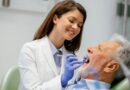 Dentista realizando atendimento em paciente idoso em consultório odontológico, representando a profissão e informações sobre quanto ganha um dentista na Espanha.
